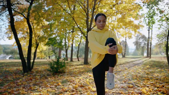 Girl Exercising and Stretching Before Morning Run at the Park in Autumn