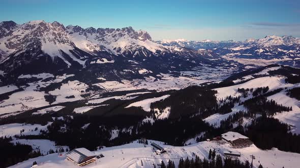 Snowy mountains in low clouds and blue sky at sunset in winter. Panoramic landscape with beautiful s