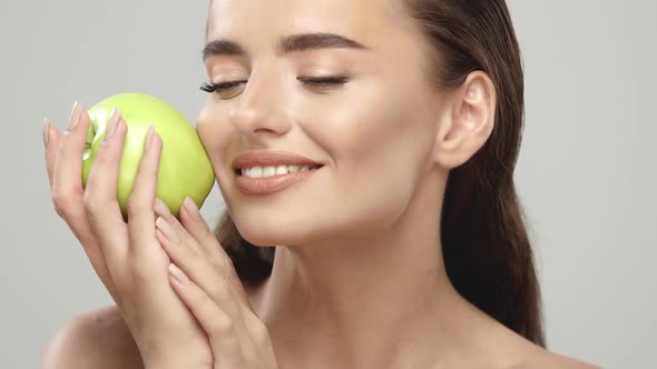 Cheerful Girl Stroking Her Face with Fresh Apple