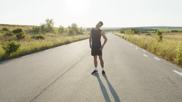 Young Athletic Man Doing Body Warm-up on Nature During Sunrise in Summer