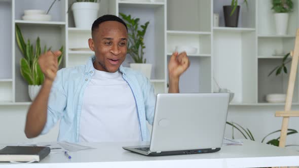 African-American Feels Happy Received Great News By Internet Looks at Pc Screen Raised Hands Scream