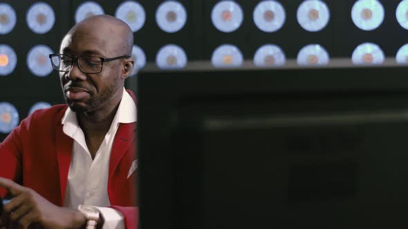 Nicelooking Africanamerican Businessman in Red Suit Looks at His Smartphone