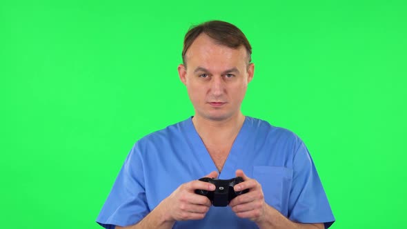 Medical Man Playing a Video Game Using Wireless Controller and Rejoicing in Victory. Green Screen