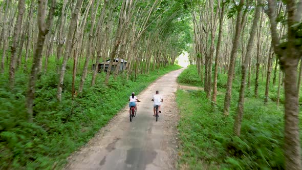 Couple Men and Women on Bicycle at a Rubber Plantation in Thailand
