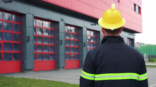 A Firefighter (The Back To the Camera) Looks at a Fire Station