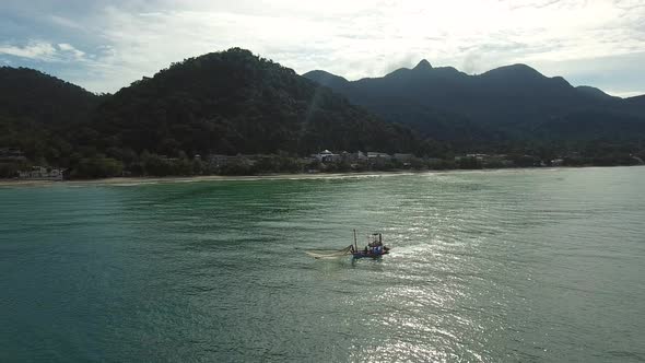 Aerial view of small fishing boat navigating on calm water, Ko Chang, Thailand.