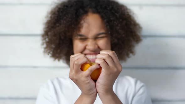 Happy Young Black Woman Ripping Orange in Half