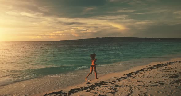 Silhouette of Girl in Bikini Swimsuit Running at Sunset Slow Motion Aerial