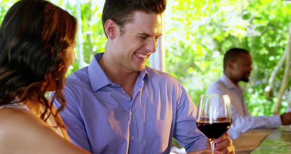 Two couples interacting with each other while having drinks at counter