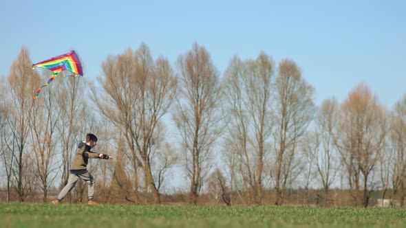 A Boy Runs Across a Green Field with a Kite