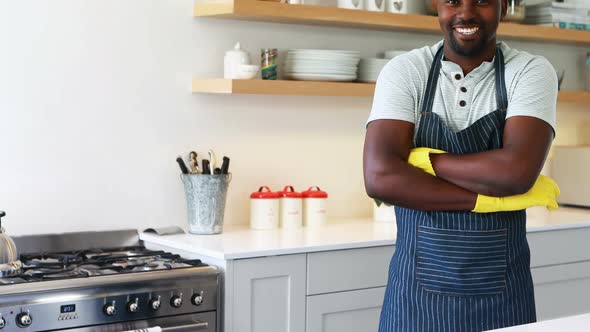 Smiling man standing with arms crossed in kitchen
