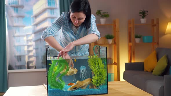 Young Woman Decorates Aquarium in Home