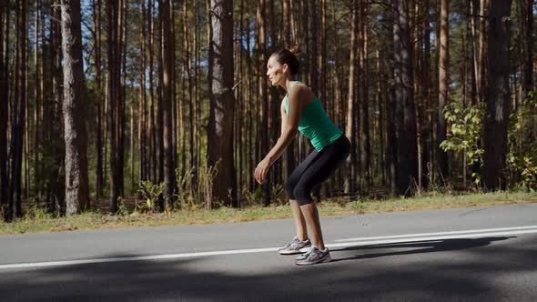 girl performs a squat on an asphalt road in the forest