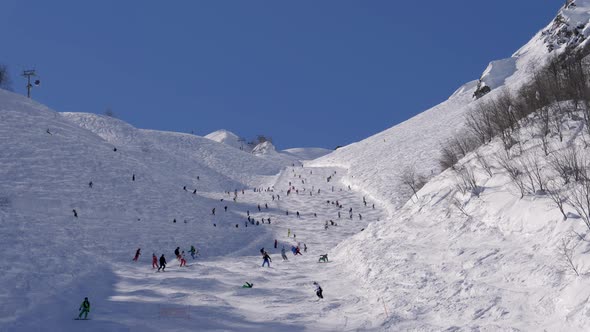 Many Skiers And Snowboarders Skiing Down Snow Ski Slope In Mountains In Winter