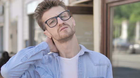 Casual Young Man with Neck Pain Standing Outdoor