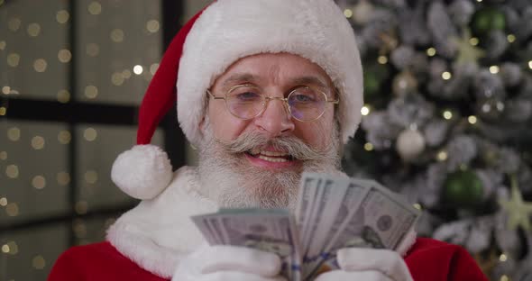 Closeup Portrait of a Cheerful Santa Claus Rejoicing Counting Paper Banknotes in His Residence