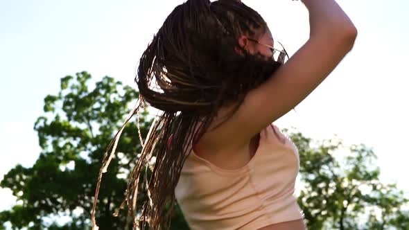 Back View of Young Beautiful Girl with Dreads Dancing in a Park