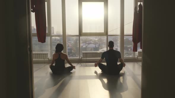 Man and Woman Practice Yoga Meditation in a Spacious Class at Sunrise