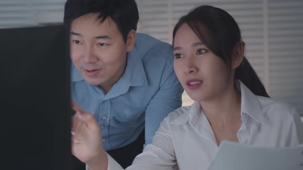 Asian Businessman and Businesswoman looking at desktop computer screen working together