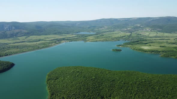 Aerial View on Water Reservoir at Mountain Valley Covered with Green Spring Forest