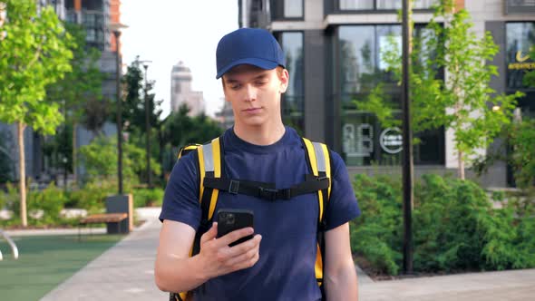 Food Delivery Man Courier Walks Street Watching Navigation in Smartphone