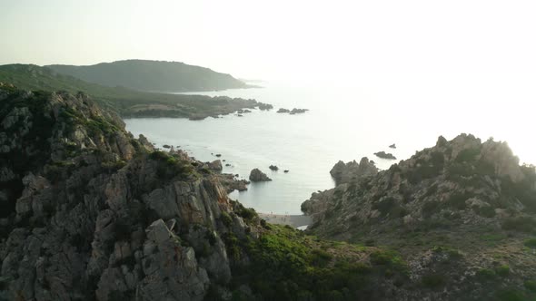 revealing aerial shot of exotic small beach between mountains on Italian Sardinia island