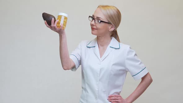 Nutritionist Doctor Holding Organic Avocado Fruit and Jar of Medicine or Vitamin or Omega 3 Capsules