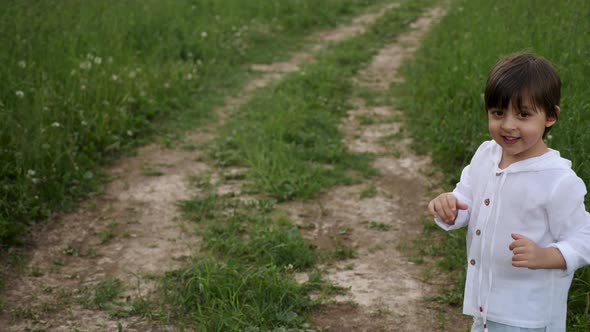 Boy in Blue Pants and a White Jacket in a Hood Runs Along the Road