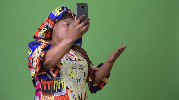 Overweight Beautiful African Woman Wearing Traditional Clothing Against Green Background