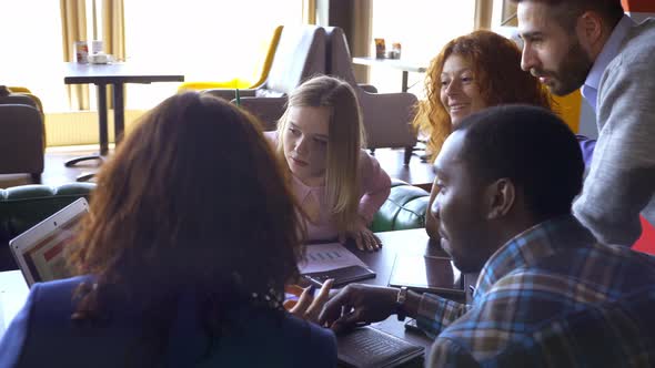 Business, Startup and People Concept - Happy Creative Team with Computers and Folder Discussing