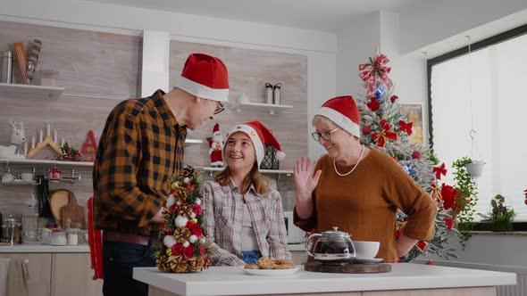 Grandparents Celebrating Christmastime with Grandchild Bringing Xmas Wrapper Surprise Present