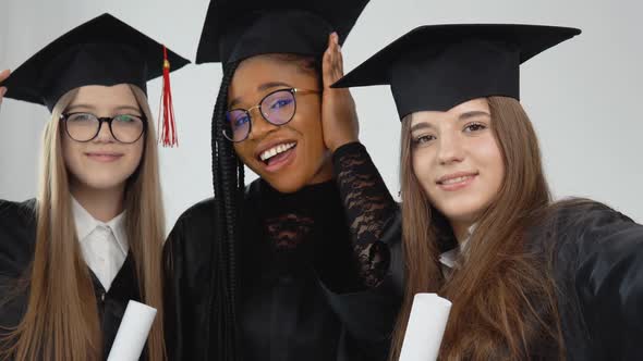 Three Young Happy Graduate Women of Different Nationalities Stand Together Side By Side with