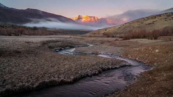 Time lapse of fog moving over landscape with winding river and mountain