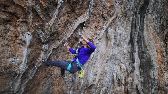 Slow Motion Smiling Tired Woman Rock Climber Hanging on Rope on Hard Challenge Route on Overhanging