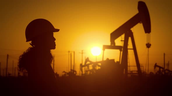 Woman engineer inspects oil pumps at sunrise