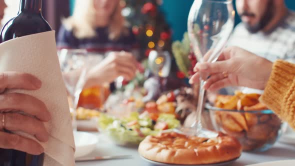 Man's Hand Holds Bottle of Red Wine in Napkin and Pours Wine Into Glass in Front on Background