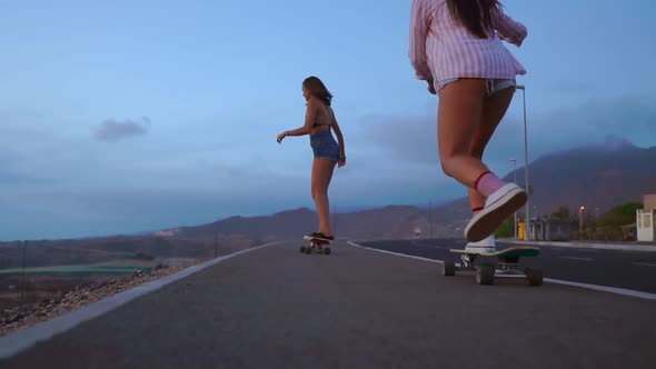 Close - Up of a Skateboard and Two Girls Who Are Riding on Boards From a Mountain on a Background of