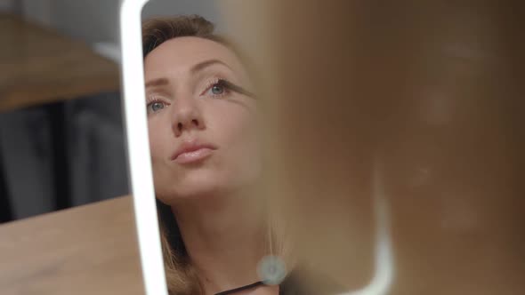 A Beautiful Young Woman Looks at Her Reflection in the Mirror