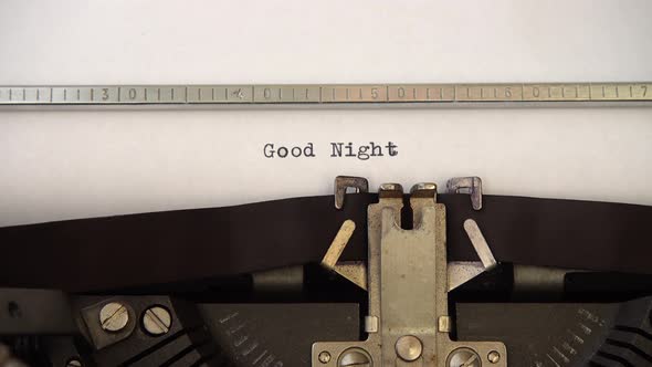 Typing phrase Good Night on retro typewriter. Close up.