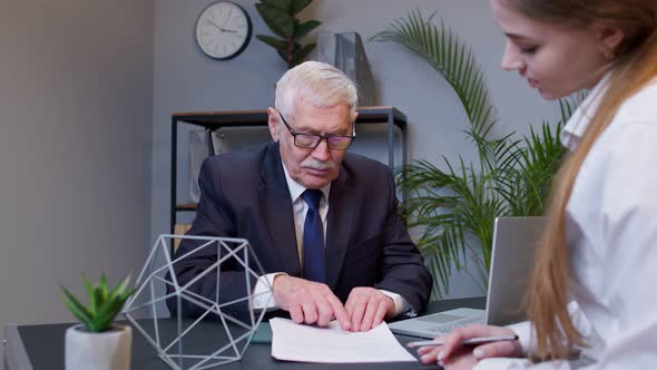 Senior Businessman Company Director Explaining Documents Discussing Project with Woman Colleague