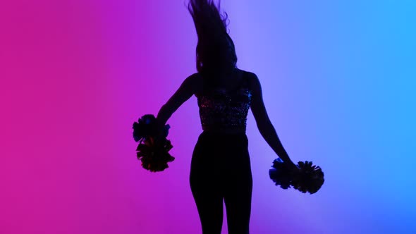 Silhouette of Slender Cheerleader Dancing Energetically with Pompoms in Hands Against Background of