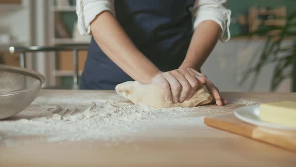 Professional Chef Kneads Dough for Baking on a Wooden Kitchen Table