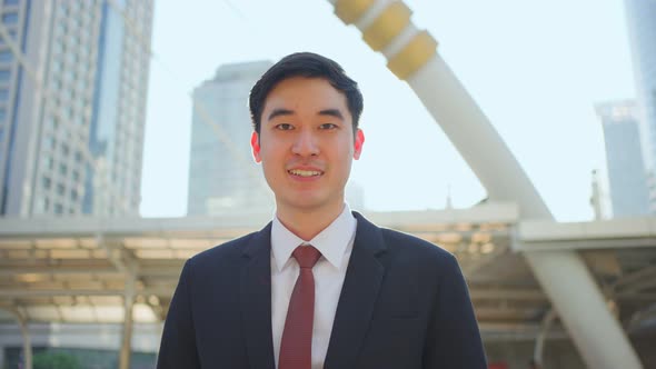 Asian handsome smart businessman standing outdoor with smile, working in company office in city.