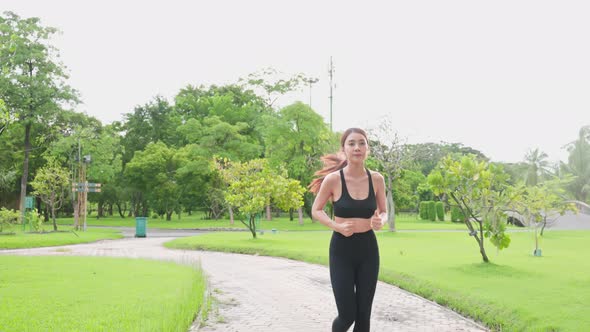 Asian young beautiful sport woman running on street in public park.