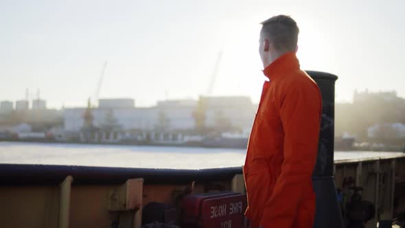 Harbor Worker in Orange Uniform Standing By the Board of the Ship