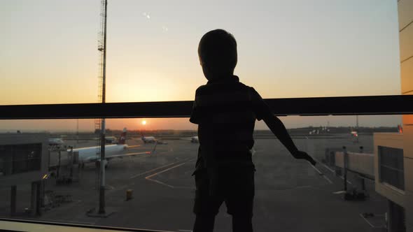 Silhouette of Child Boy in Front of Window with Airport