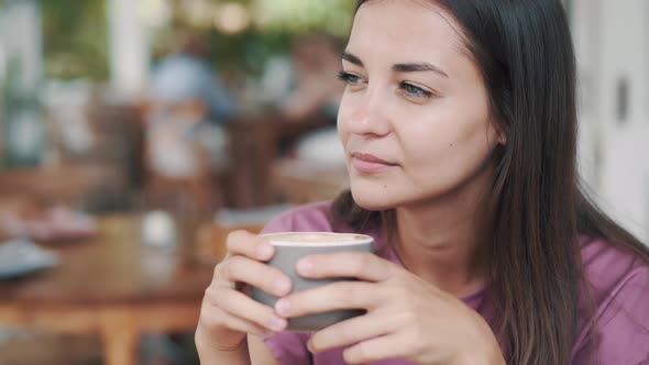 Portrait of Beautiful Woman Drinking Hot Beverage From Cup in Cafe and Smiling