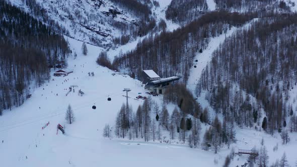 Wide aerial of active ski lifts with cable cars on a resort in the Swiss mountains