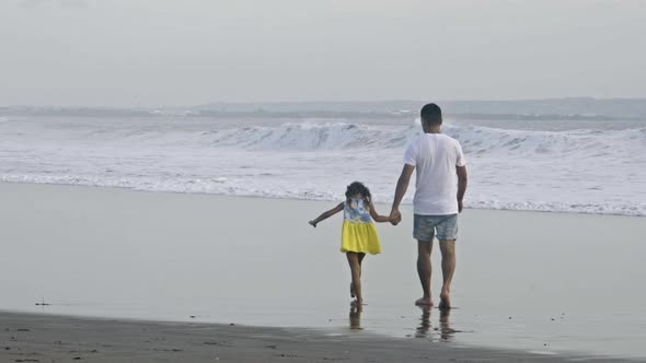 Dad and Little Daughter Walking on Ocean Shore alt