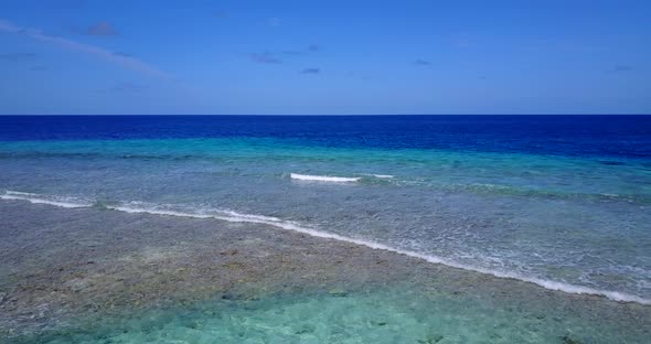 Wide aerial clean view of a sandy white paradise beach and aqua blue water background 